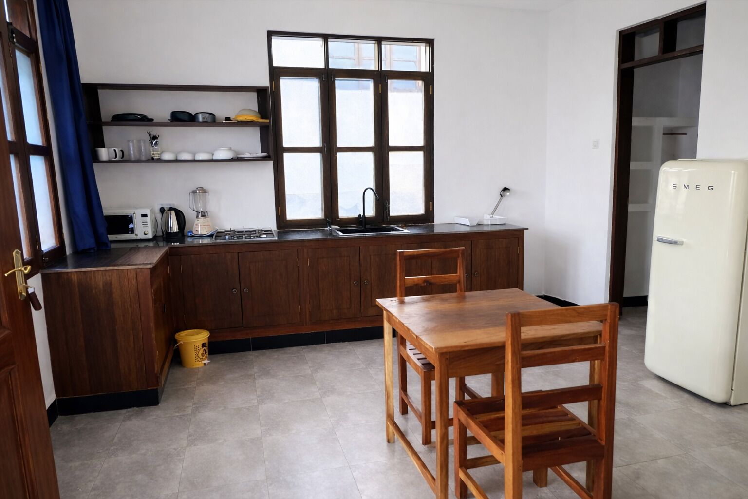 Μια μικρή κουζίνα με ξύλινα ντουλάπια, έναν νεροχύτη, μια κουζίνα και ένα ψυγείο.