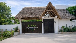 A building with a thatched roof and a black gate labeled 'MAJANI BREEZE ZANZIBAR'. - Majani Breeze Zanzibar (Nungwi)