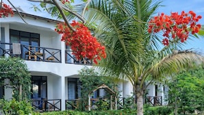 A two-story building with balconies, surrounded by lush greenery and flowering plants. - Majani Breeze Zanzibar (Nungwi)