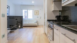 Une cuisine moderne avec un plan de travail noir, des appareils en acier inoxydable et un canapé blanc en arrière-plan.