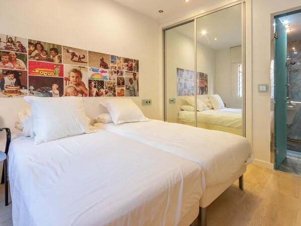 A bedroom with a large bed, a chair, and a wall adorned with photographs.