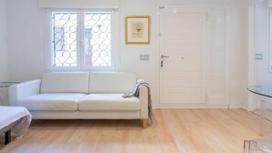 Un salon minimaliste avec un canapé blanc, une table en verre et une porte.
