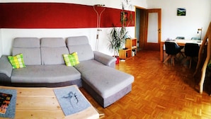 A living room with a grey sofa, wooden coffee table, and a dining area with a table and chairs. - Apartment 'Villingen' with Balcony and Wi-Fi (Villingen-Schwenningen)