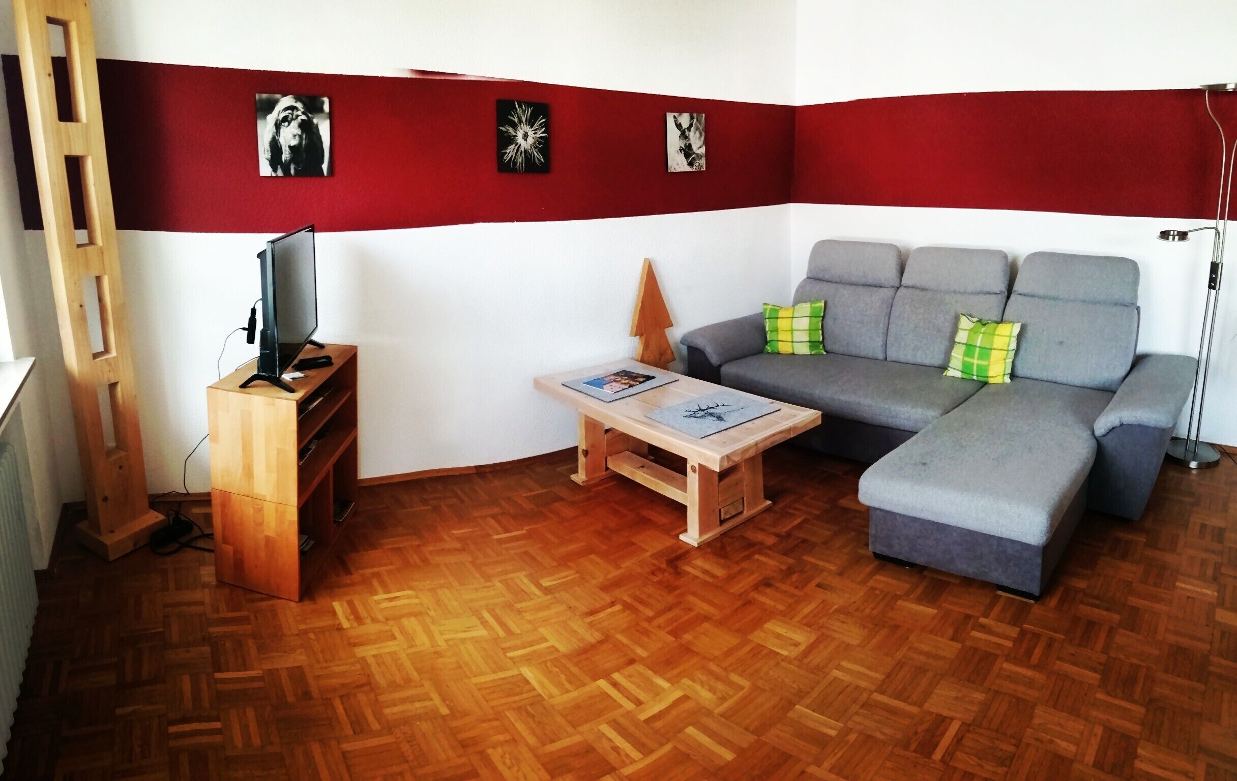 Ein Wohnzimmer mit einer Couch, einem Couchtisch, einem Fernseher und Holzboden.