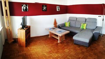 Ein Wohnzimmer mit einer Couch, einem Couchtisch, einem Fernseher und Holzboden.
