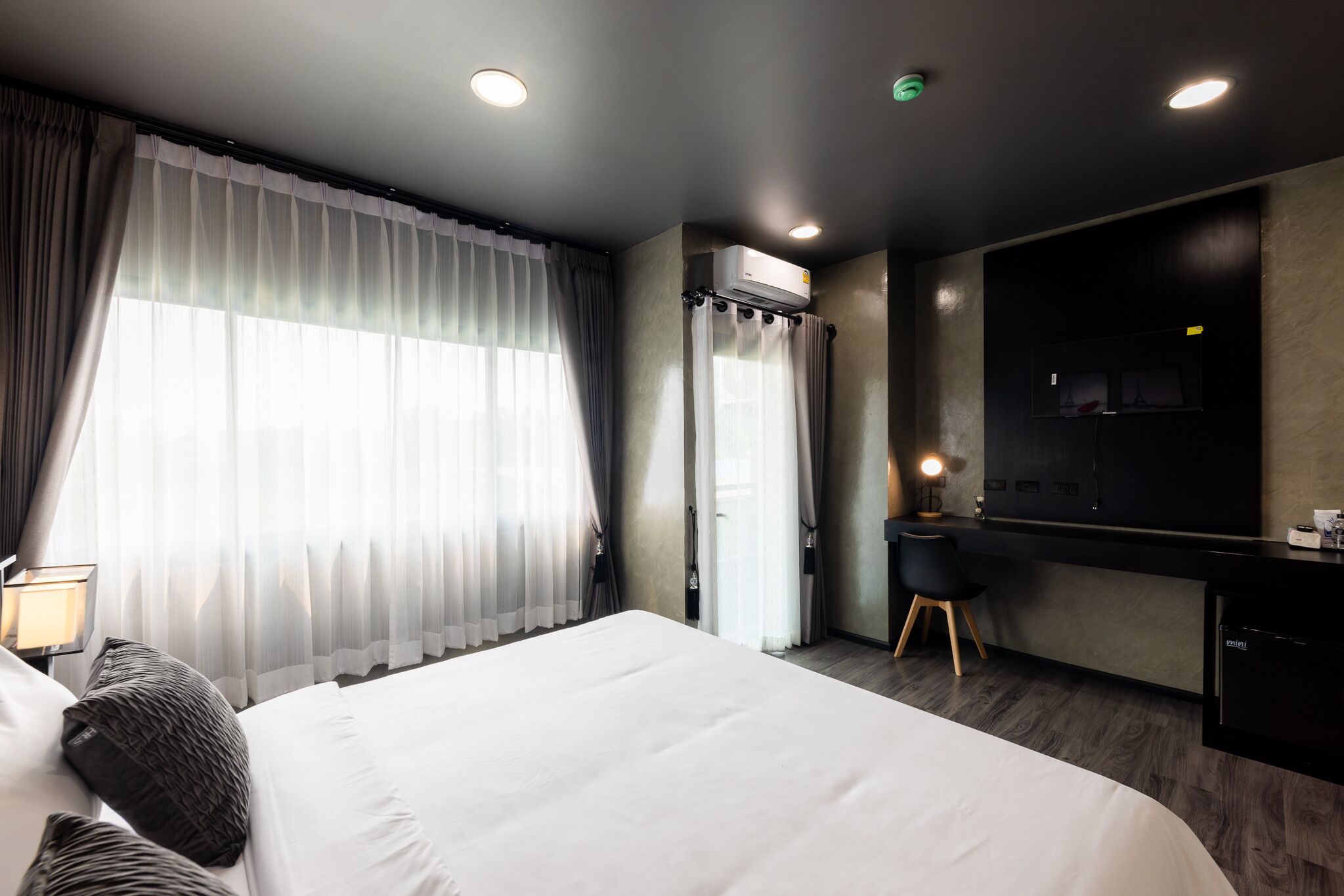 Una camera d'albergo moderna con un letto grande, una scrivania e una televisione.