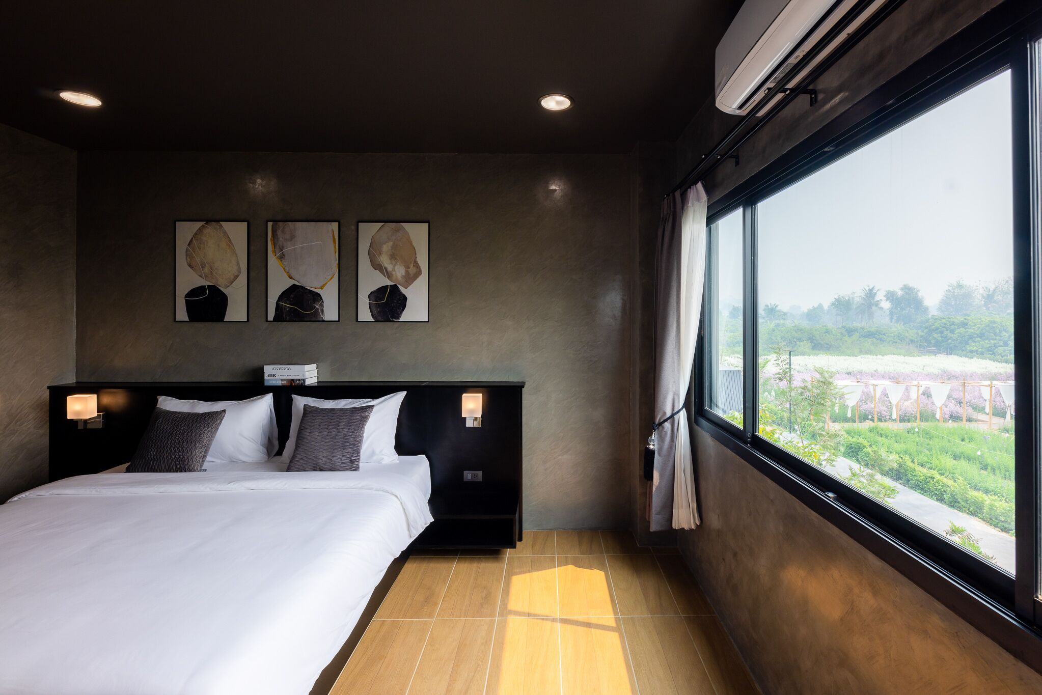 Een moderne hotelkamer met een groot bed, een nachtkastje met lamp en kunst aan de muur.