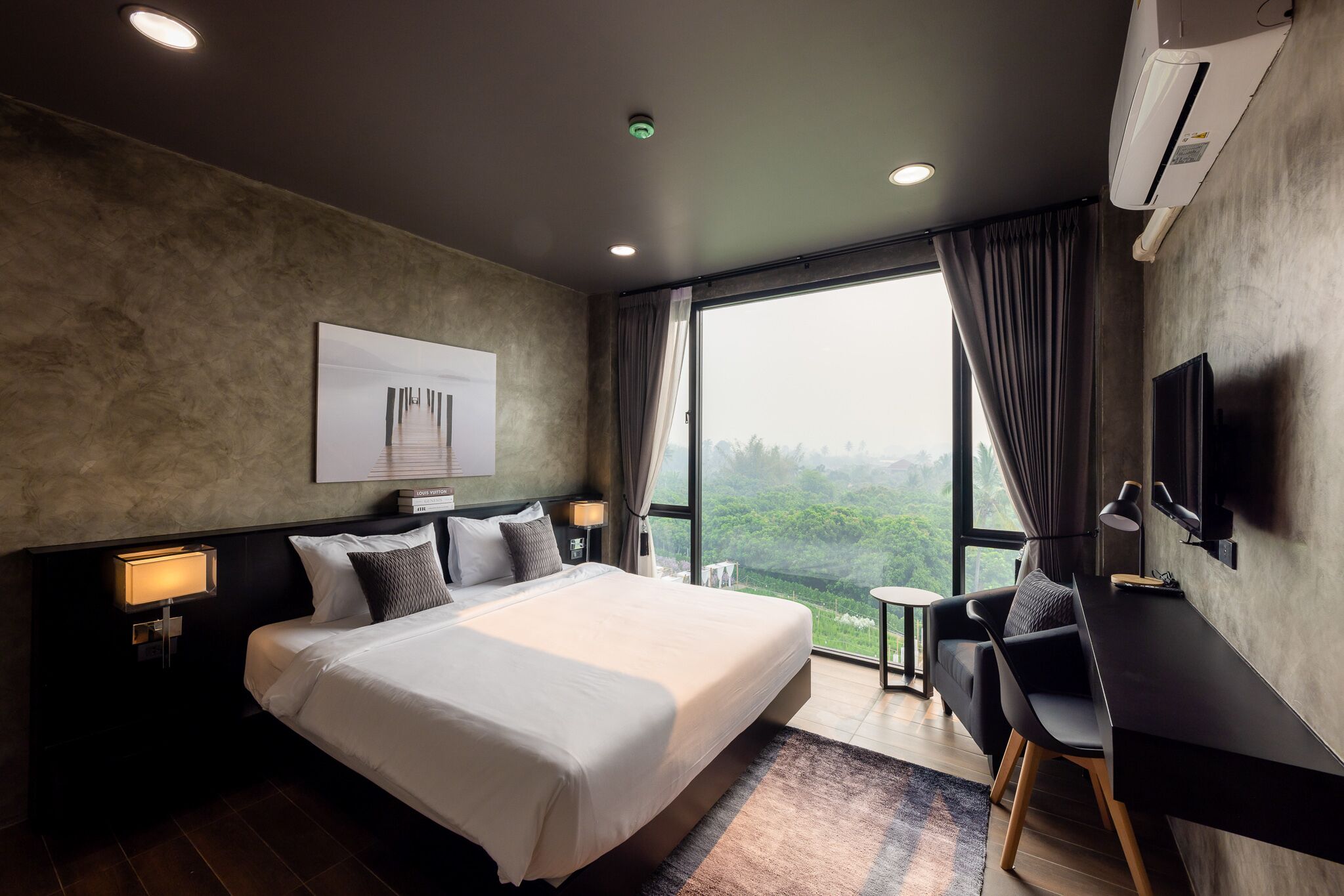 A modern hotel room with a large bed, bedside lamps, a desk, and a view of the outdoors.