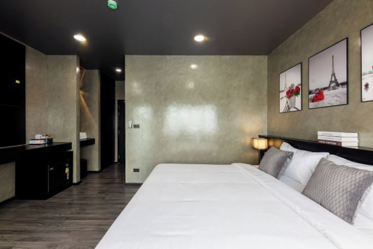 Una habitación de hotel moderna con una cama grande, un escritorio y un televisor montado en la pared.