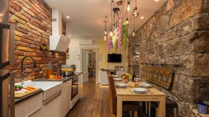 A modern kitchen with a brick wall, wooden flooring, and a dining area with a table set for two. - Rustic Villa Okra With Pool, Opatija - Ičići, Croatia (Opatija - Ičići)