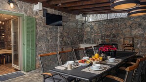 A dining area with a stone wall, wooden beams, and a table set for breakfast. - Rustic Villa Okra With Pool, Opatija - Ičići, Croatia (Opatija - Ičići)