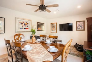 A dining area with a wooden table, chairs, and a ceiling fan.