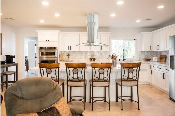 A modern kitchen with white cabinets, stainless steel appliances, and a central island with bar stools.