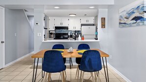 Eine moderne Küche mit weißen Schränken, einem Holztisch und blauen Stühlen.