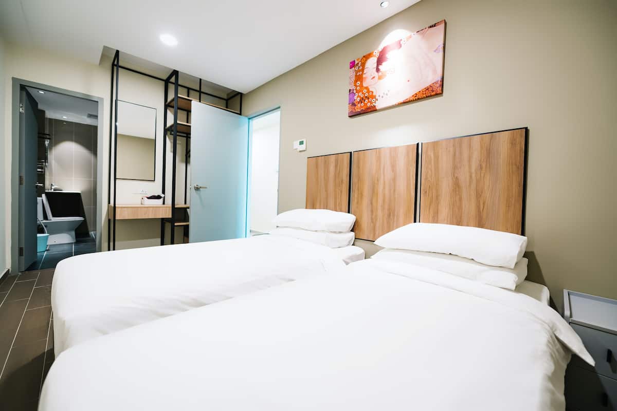 A modern hotel room with two beds, a desk, and a bathroom.
