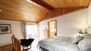 A bedroom with a wooden ceiling, a bed with patterned bedding, a chair, and a dresser. - Cottage W LAKE VIEWS, beside waterfront trail and steps from beach (Barrie)