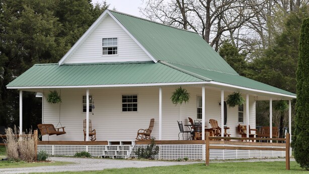 A white house with a green roof, a porch with wooden furniture, and a white fence. - Good Hope Cottage- Amish Country / fire pit (Lawrenceburg)