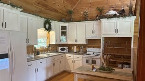 A kitchen with white cabinets, a wooden countertop, a stove, and a sink. - Good Hope Cottage- Amish Country / fire pit (Lawrenceburg)