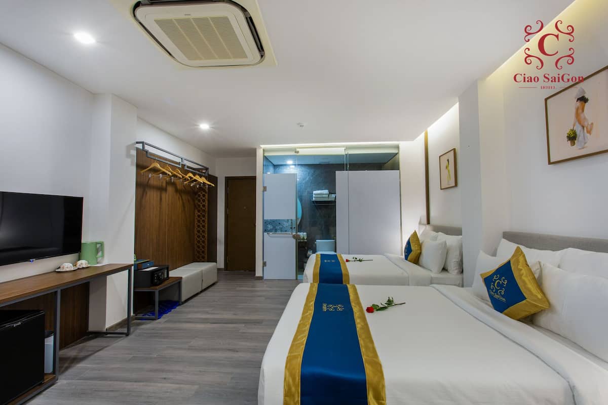 Hotellihuone, jossa on televisio, työpöytä, vaatekaappi ja kaksi sänkyä, joissa on sinivalkoiset ja kultaiset päiväpeitteet.