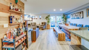 Une cuisine moderne avec des étagères en bois, un coin repas avec des chaises bleues et une grande fenêtre.