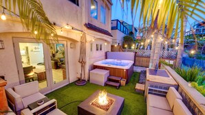 Une terrasse avec des sièges extérieurs, un foyer et un jacuzzi.