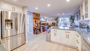 Une cuisine moderne dotée d’appareils électroménagers en acier inoxydable, d’un îlot central et d’un coin salon confortable avec une cheminée.