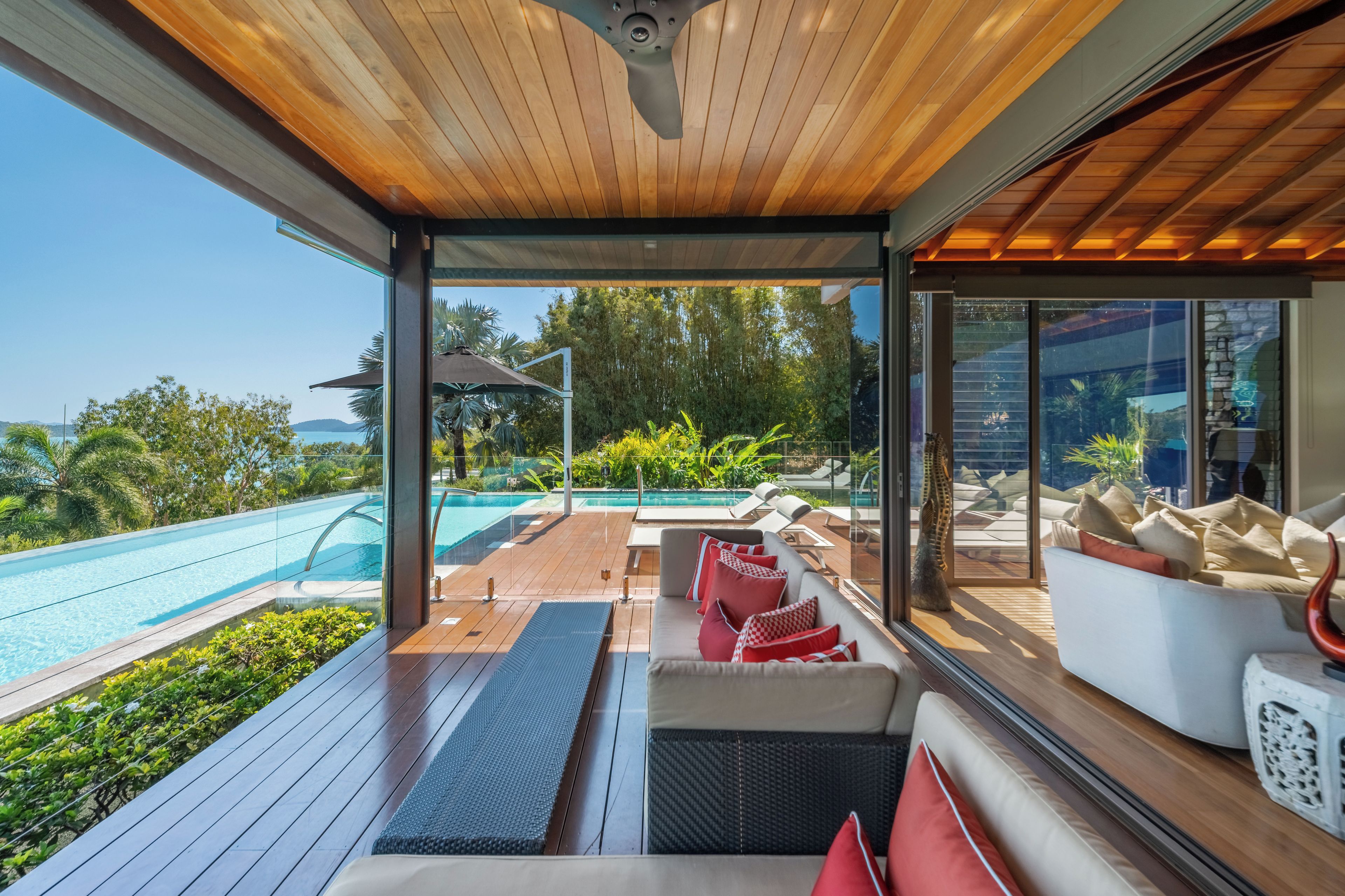 A modern outdoor lounge area with a pool, wooden deck, and seating.