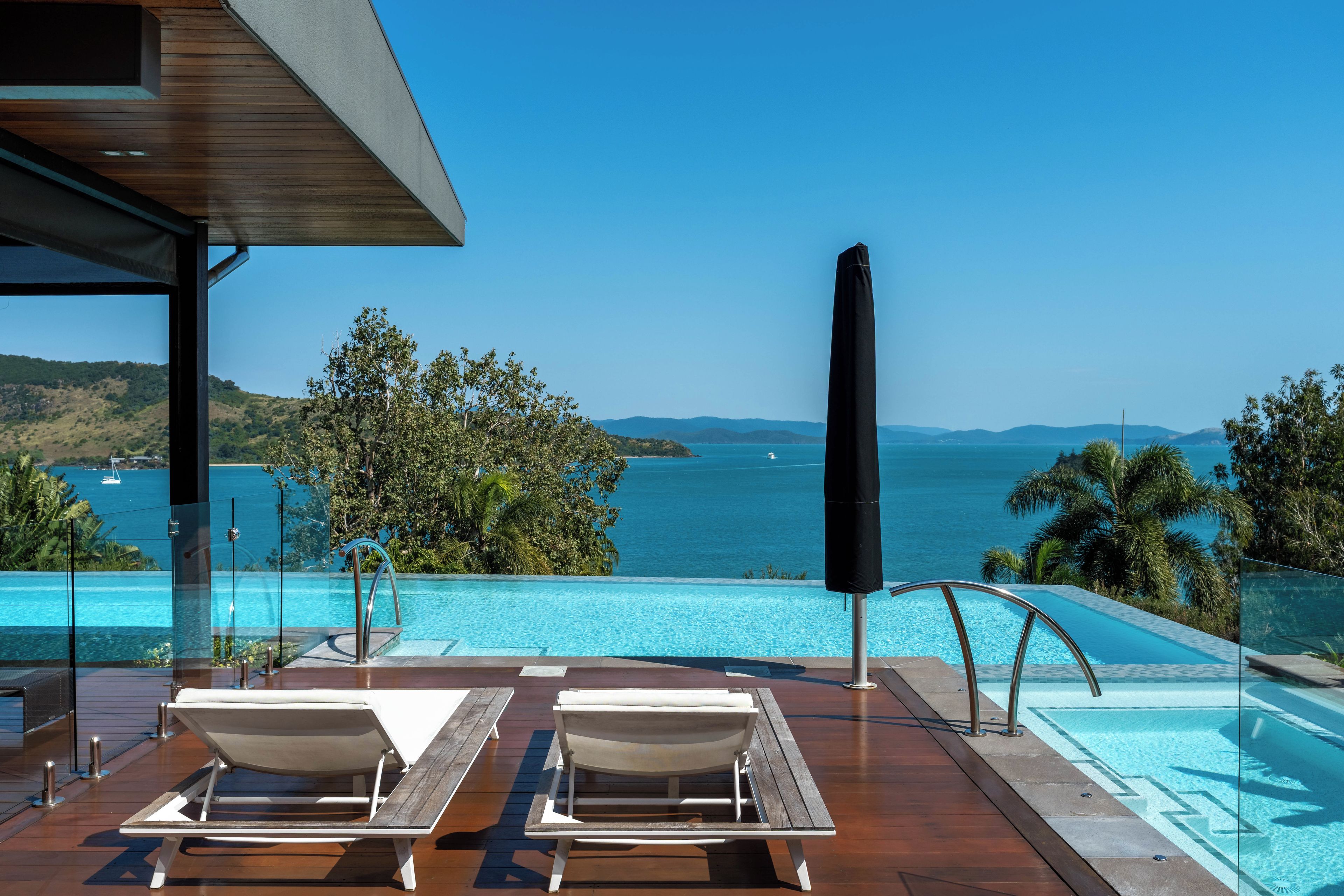 Una piscina a sfioro con lettini prendisole e vista sul mare.