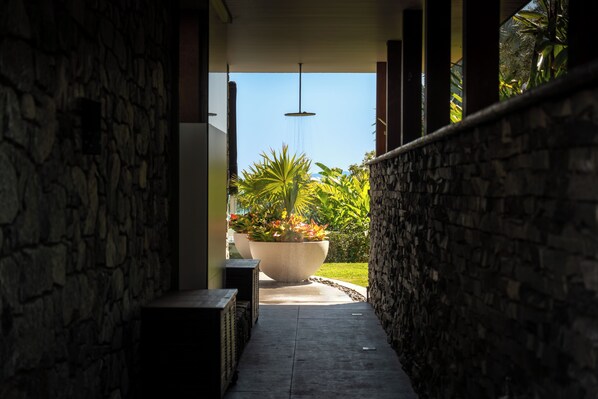 A covered walkway with stone walls, a large planter with plants, and a hanging light fixture.