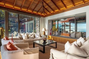 A modern living room with a sofa set, a coffee table, and large windows offering a view of the outdoors.