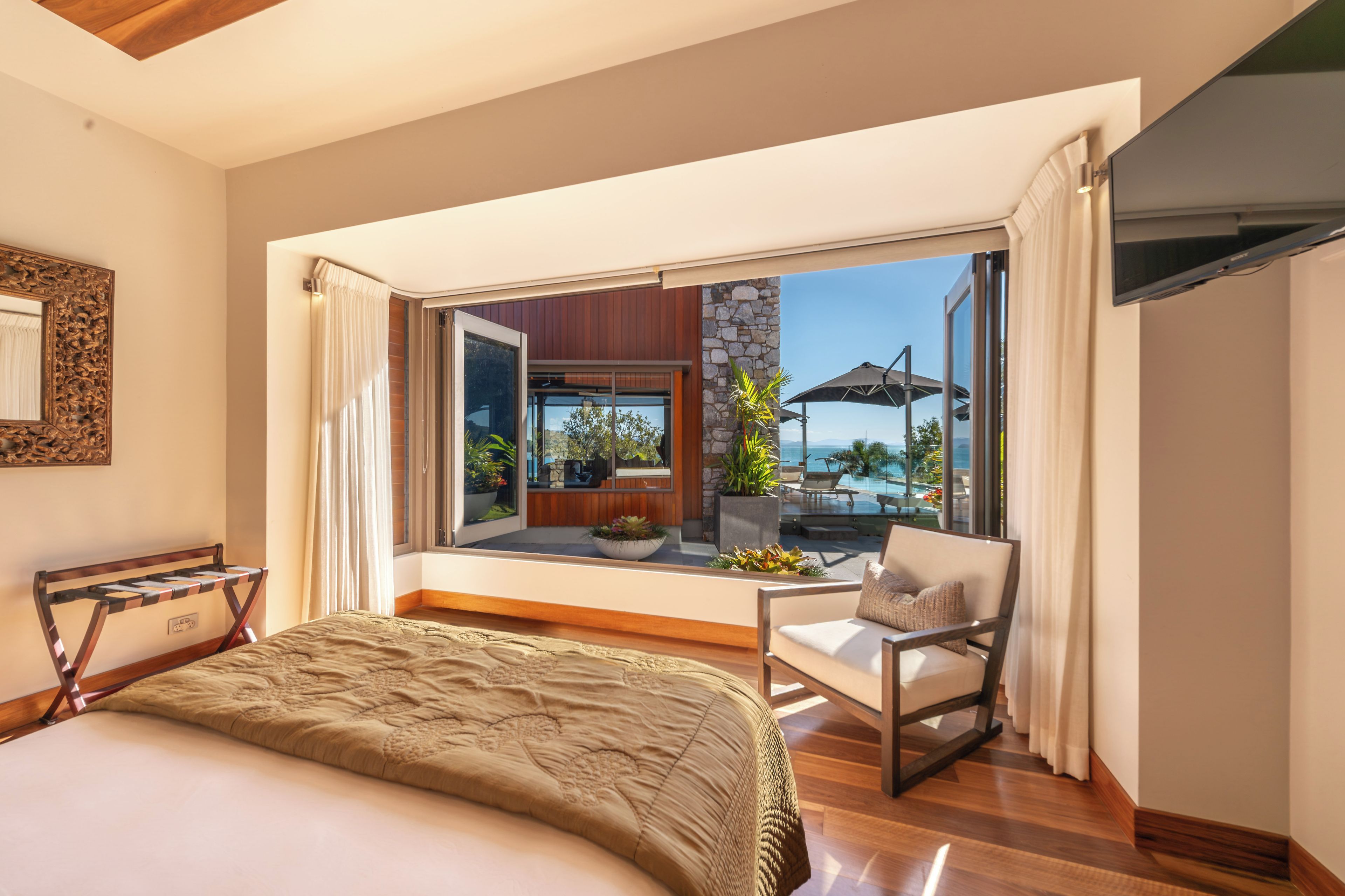 A hotel room with a large window, a bed, a chair, and a view of the outdoors.