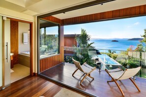 Et moderne værelse med en stor skydedør, der fører ud til en balkon med havudsigt.