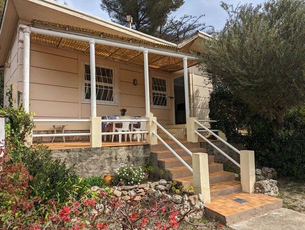 A two-story building with a covered porch, outdoor seating, and a stone pathway leading to the entrance.