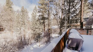 Un paisaje nevado con una terraza de madera y árboles cubiertos de nieve.