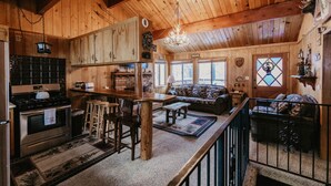 Interior rústico de una cabaña con cocina, comedor y sala de estar.