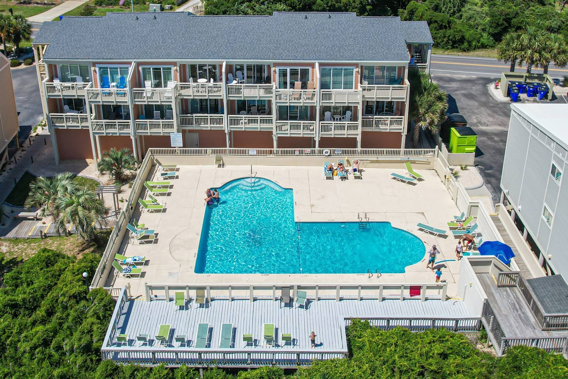 A multi-story hotel with a pool area, including lounge chairs and a children's play area.