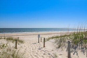 A sandy beach path leading to the ocean with a sign warning to leave it as it is.
