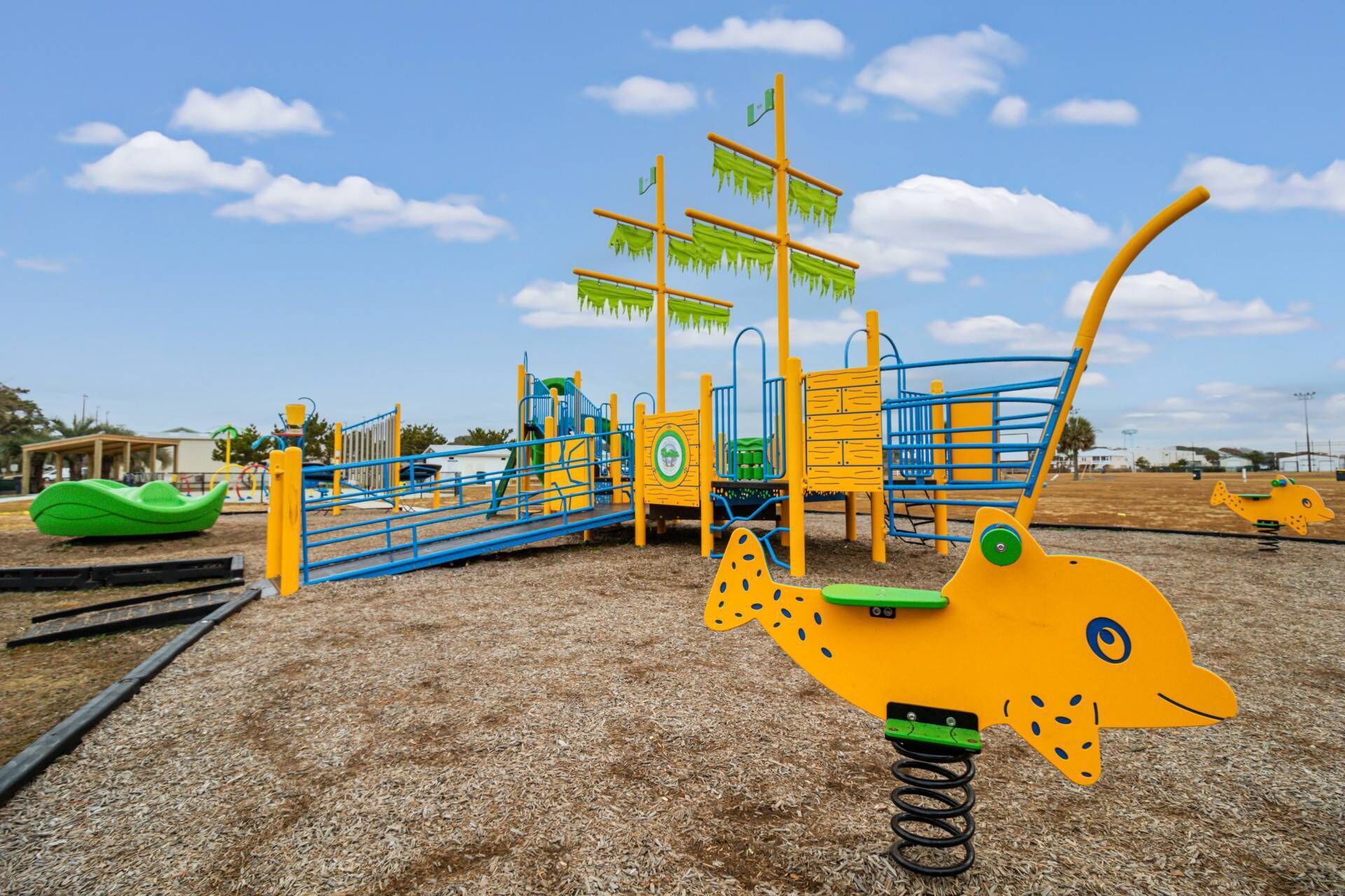 A playground with a slide, climbing structures, and a large yellow fish-shaped swing.