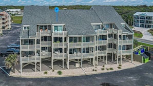 A multi-story hotel with balconies, a parking lot, and a view of the surrounding landscape.