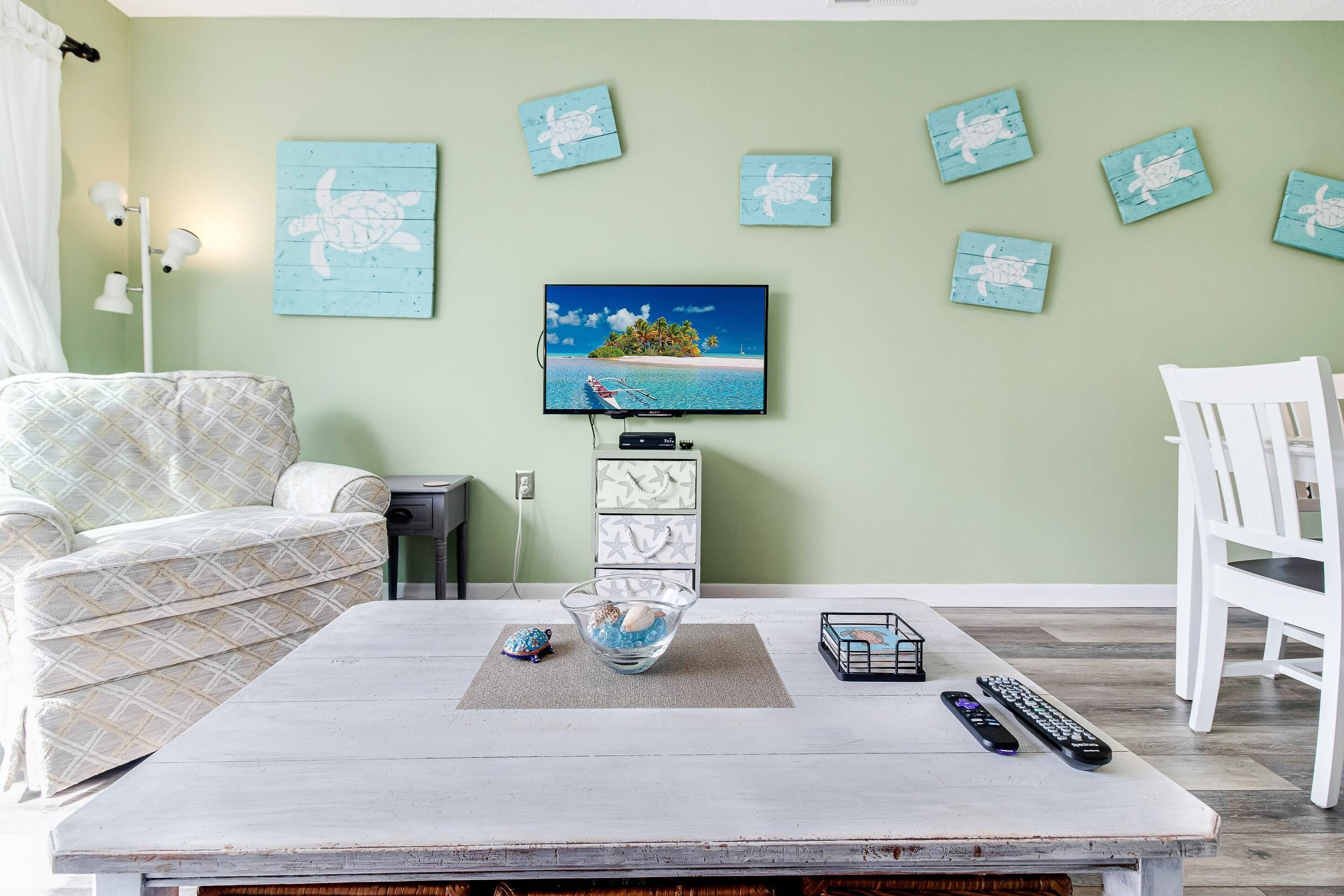 Een woonkamer met een televisie, een bank, een salontafel en een eettafel.
