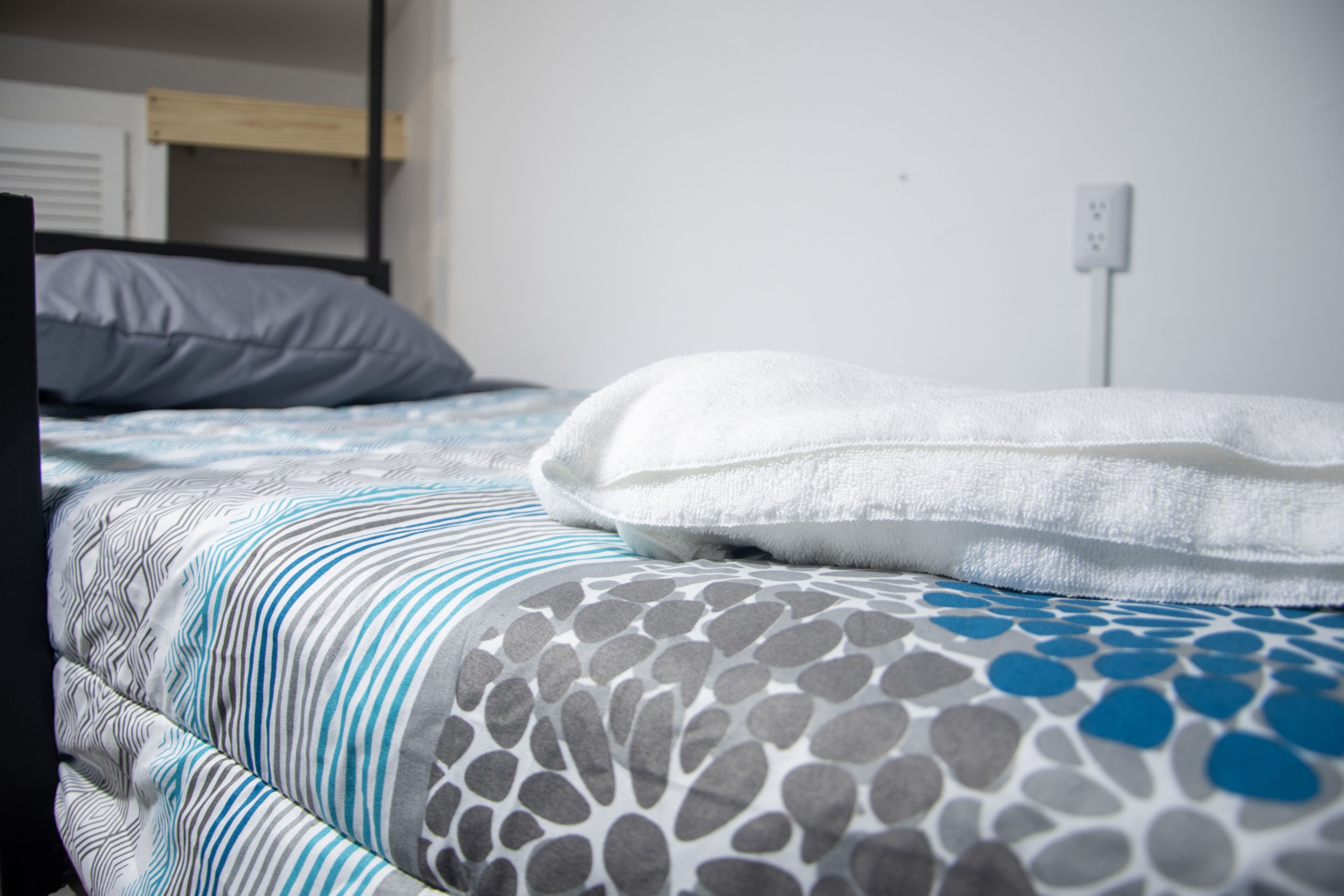 A bed with striped bedding and a patterned pillow.