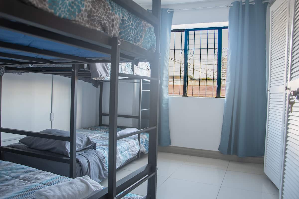 A bunk bed room with a window and curtains.