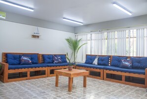 Una zona de recepción con dos sofás de madera con cojines azules, una mesa de centro de madera y una planta en maceta.