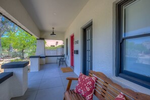 Un espacio exterior cubierto con un banco, una puerta y una ventana.
