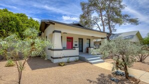A modern house with a red door, number 1240, surrounded by a landscaped garden with various plants and trees.