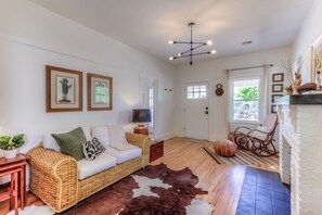 A living room with a sofa, a coffee table, a fireplace, and a cowhide rug. - Cute remodeled bungalow near UA (Tucson)