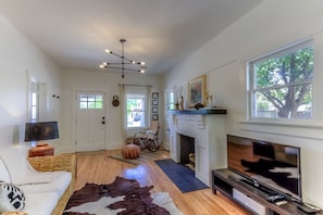 A living room with a fireplace, a television, and a large window. - Cute remodeled bungalow near UA (Tucson)