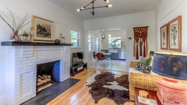 A spacious living room with a white brick fireplace, a cowhide rug, and a modern chandelier.