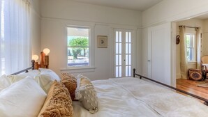 A bedroom with a large bed, a window with a view, and a door leading to another room.