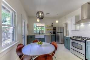 A modern kitchen with a central island, stainless steel appliances, and a view of the outdoors.